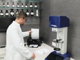 Prozess Ein Apotheker steht vor einem schwarzen Drucker und hält ein Blatt in Richtung des Druckers.